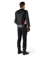 Rider viewed from the back wearing the Alpinestars Missile V3 Airflow Leather Jacket in Black White Red Fluo, styled with black pants and black boots, featuring extensive perforated leather for ventilation, DFS shoulder armor, and prominent Alpinestars branding on the lower back.
