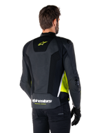 Alpinestars Missile V3 Airflow läderjacka, baksida på manlig modell, svart med fluorescerande gula och vita detaljer, omfattande perforerat läder och meshpaneler på ryggen, gul stjärnlogotyp och vit 'RACING AHEAD'-text, svarta handskar och byxor