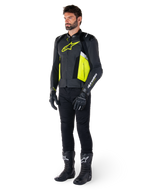 Manlig modell iklädd Alpinestars Missile V3 Airflow Läderjacka i svart, gul fluo och vitt, stylad med svarta körhandskar, byxor och stövlar, vilket framhäver den perforerade läderdesignen och den racinginspirerade estetiken.