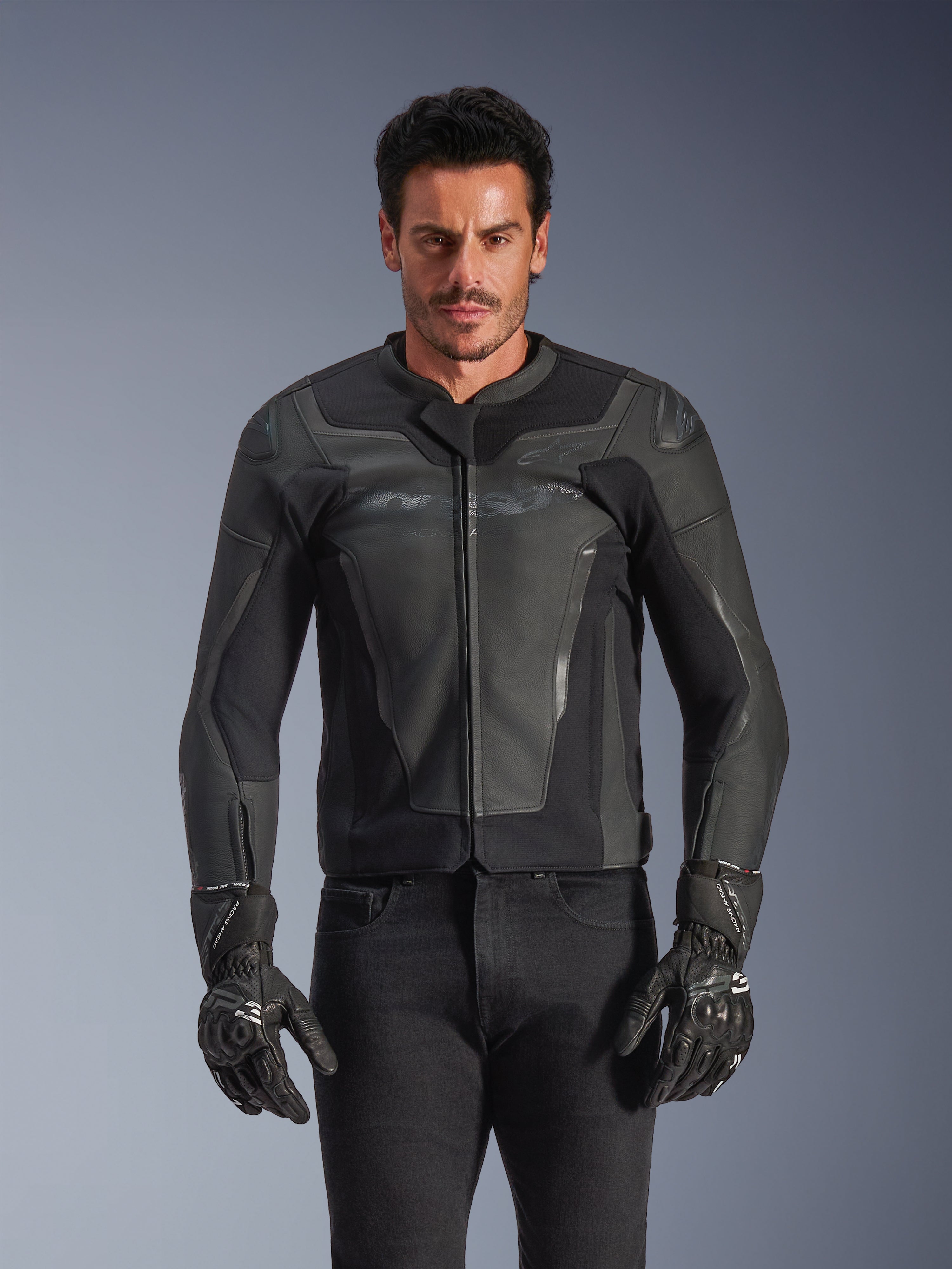 Alpinestars GP Force V2 Leather Jacket, Black and Dark Gray, motorcycle racing jacket, man wearing sleek fitted leather design with front zipper, paired with black textured gloves, modern protective gear, premium leather construction