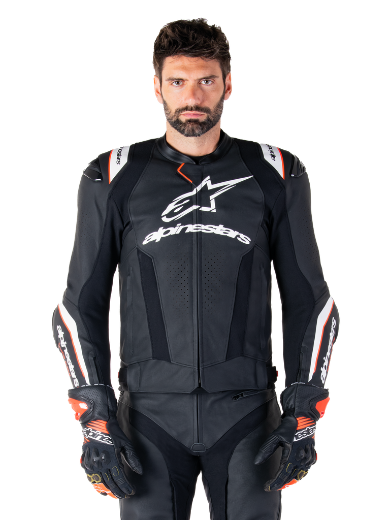 Alpinestars Missile V3 Ignition läderjacka, svart med vita och röda detaljer, bärs av en manlig modell med matchande racinghandskar och byxor, MotoGP-inspirerad sportmotorcykeljacka med tydlig logotyp