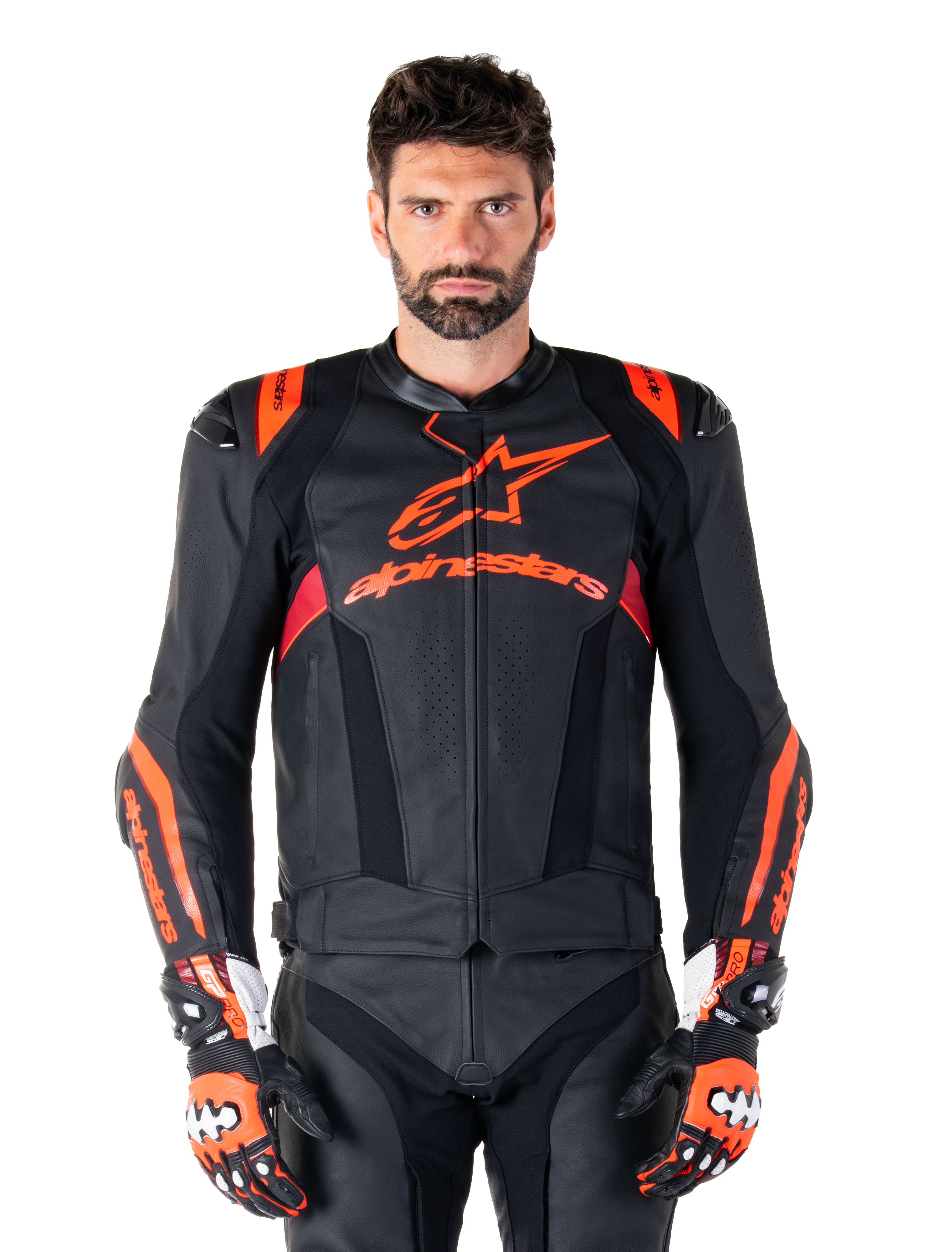 Alpinestars Missile V3 Ignition läderjacka, motorcykelracingjacka, svart och röd fluo, bärs med matchande racinghandskar och läderbyxor, med perforerad ventilation och framträdande Alpinestars-logotyper, professionell racingutrustning