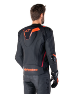 Alpinestars Missile V3 Ignition läderjacka, racingsportjacka för herrar, svart med Red Fluo-detaljer, vy bakifrån som visar den smala aerodynamiska puckeln och Alpinestars-logotyp på nedre delen av ryggen, bärs med svarta läderbyxor och racinghandskar, stilren professionell motorsportdesign