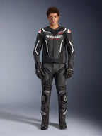 Manlig modell iklädd Alpinestars GP Force V2 Air läderjacka, svart och vit, kombinerad med matchande läderbyxor, handskar och stövlar, sportig vy framifrån, perforerad läderkonstruktion med vita detaljer och Alpinestars-logotyper