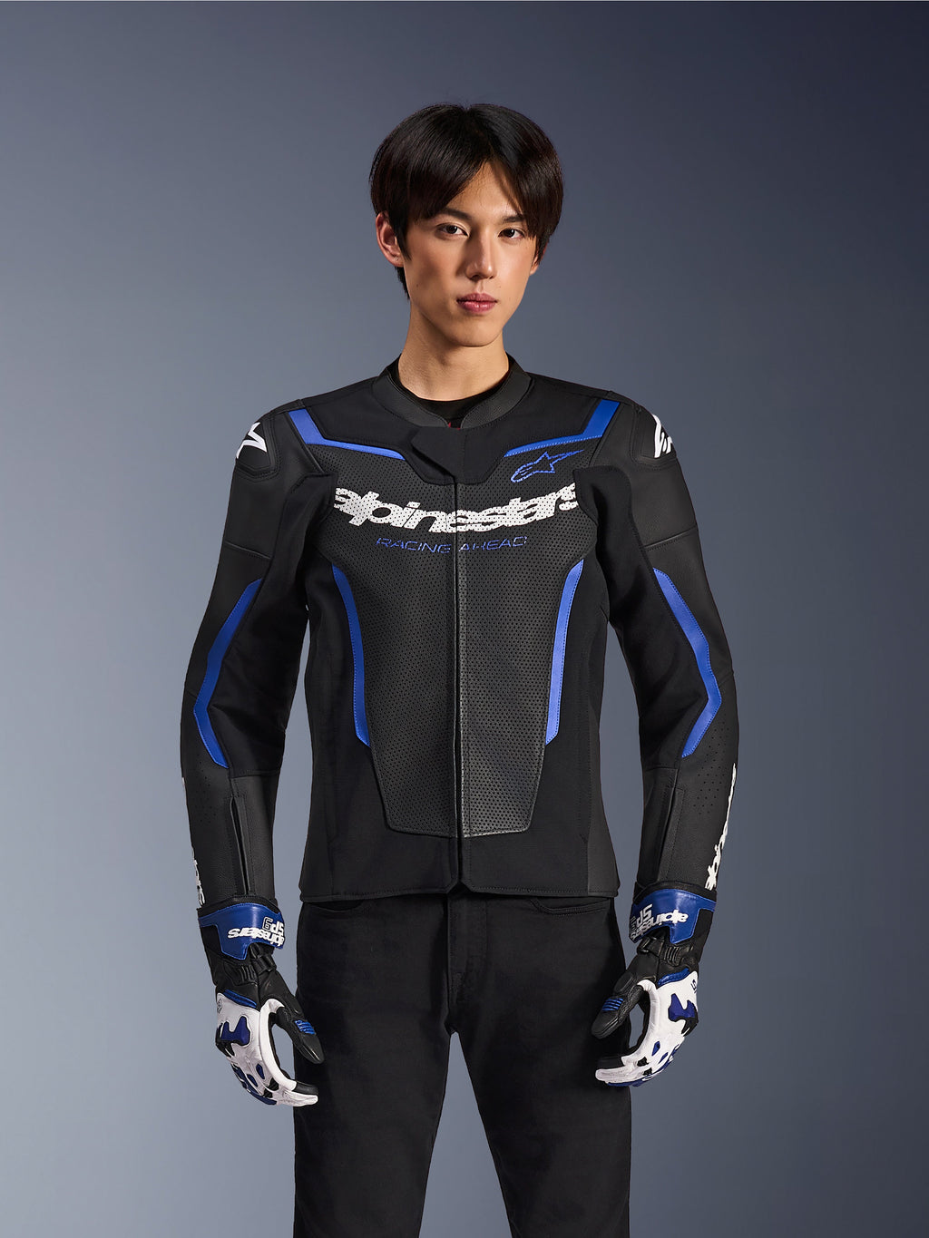 Alpinestars GP Force V2 Airflow läderjacka, Black Metallic Blue, motorcykeljacka med perforerat läder och blå detaljer, bärs av en modell med matchande racinghandskar och svarta byxor, professionell sportig körutrustning