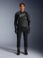 Alpinestars Dusk Airflow skinnjacka, svart och vit, motorcykeljacka i läder med perforerade paneler för luftflöde, vit Astars-logotyp på bröstet, bärs av en manlig förare med svarta byxor, handskar och mc-stövlar, professionell studiobild för sportmotorcykelutrustning.