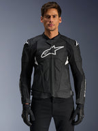 Alpinestars Dusk Airflow läderjacka, svart och vit, motorcykeljacka i läder som bärs av en modell, med perforerade läderpaneler för ventilation, en stor vit bröstlogotyp och externa axelskydd.