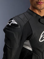 Alpinestars Dusk Airflow läderjacka, svart och vit, närbild på axel och bröst, med perforerat läder för ventilation, DFS-axelskydd med vit Alpinestars-logotyp, sportig design.