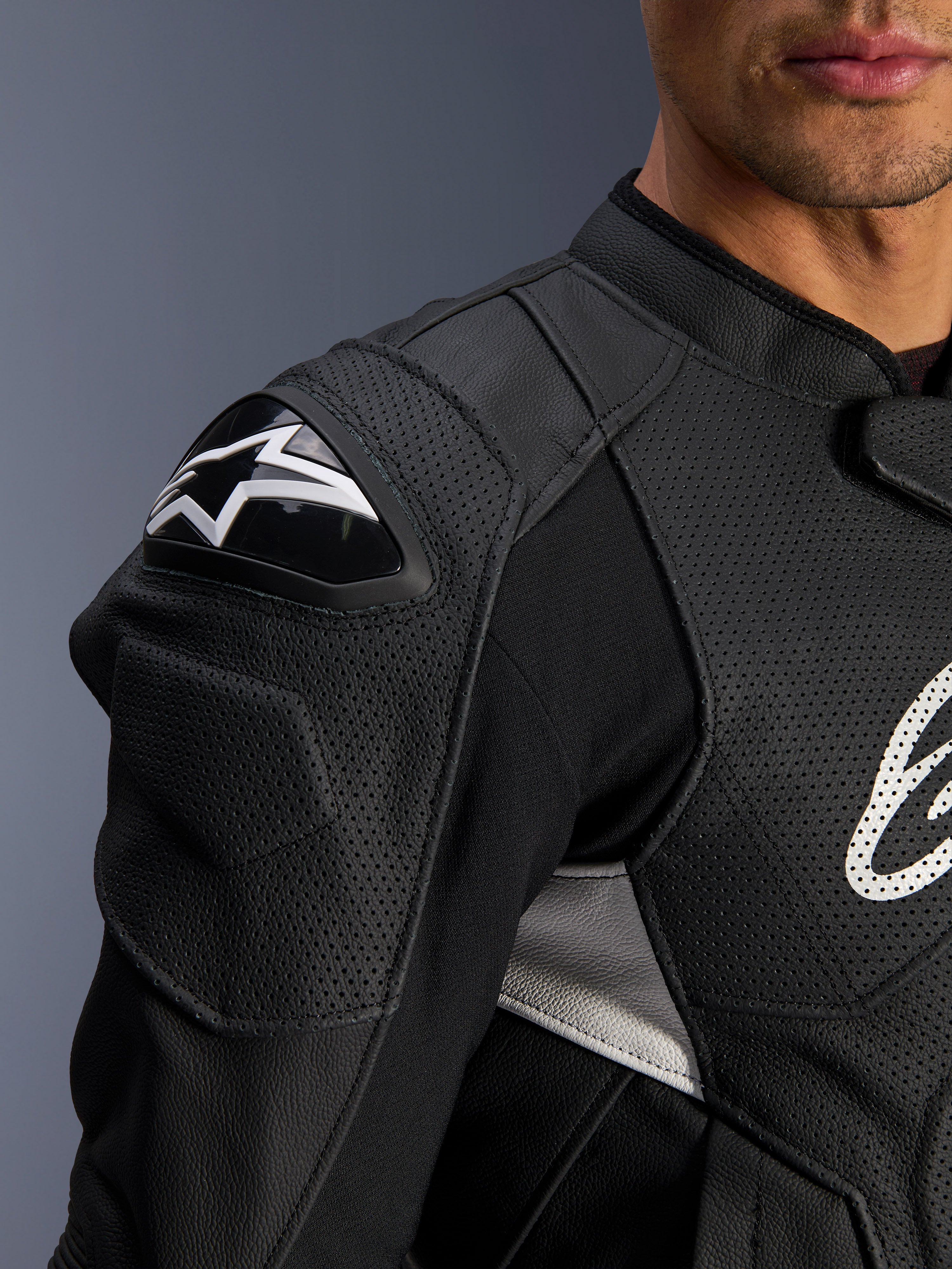 Alpinestars Dusk Airflow läderjacka, svart och vit, närbild på axel och bröst, med perforerat läder för ventilation, DFS-axelskydd med vit Alpinestars-logotyp, sportig design.