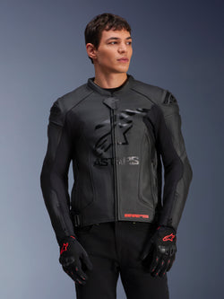 Alpinestars GP Plus R V4 Airflow läderjacka, svart motorcykelracingsjacka med perforerad läderkonstruktion, framträdande ASTARS-logotyp på bröstet och DFS-axelskydd, bärs med svarta och röda handskar