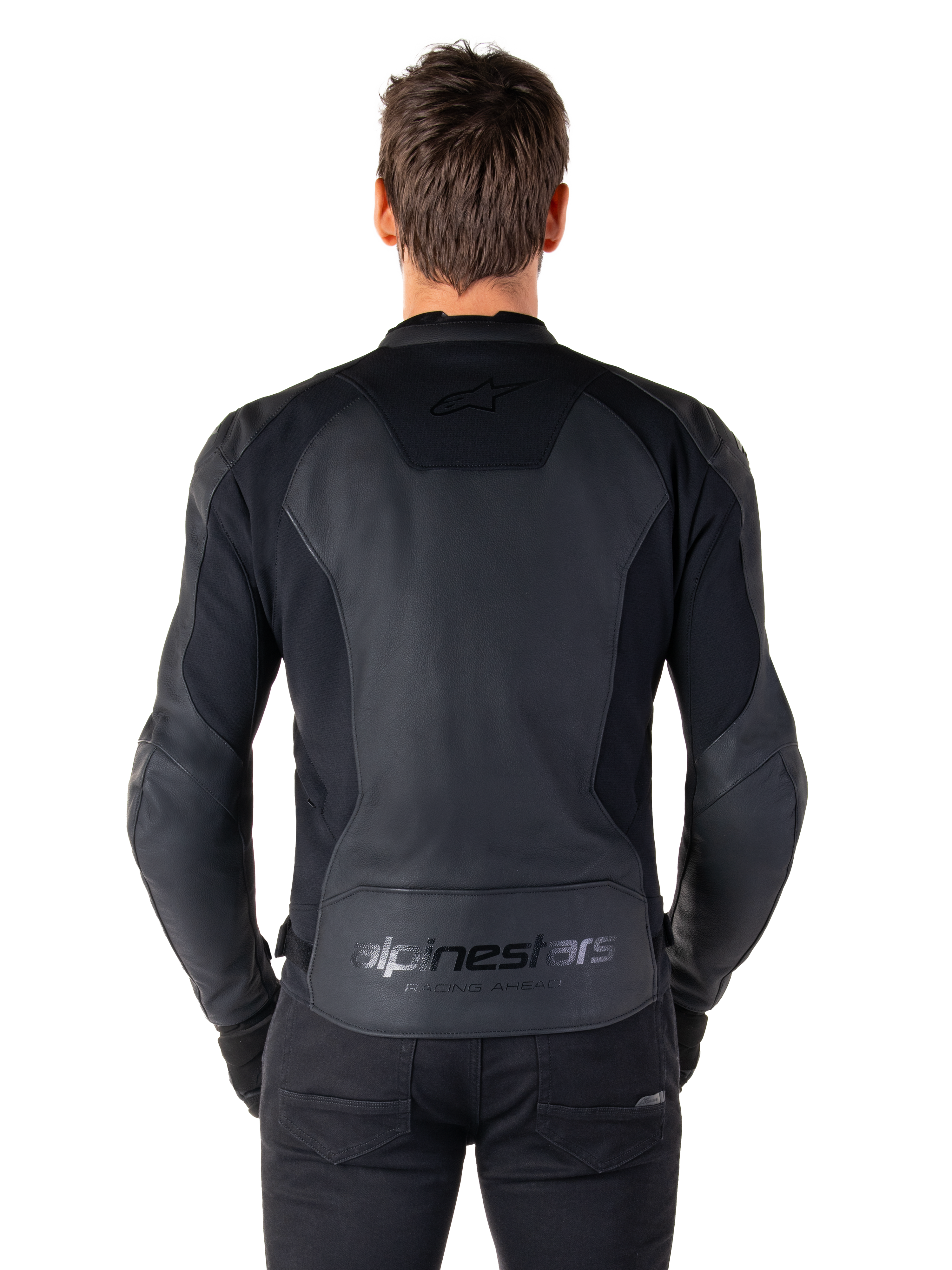 Ryggvy av en man som bär Alpinestars Faster V3 skinnjacka i Black Black, med paneler i premiumläder och flexibla stretchinsatser, subtil 'alpinestars'- och 'RACING AHEAD'-branding på nedre delen av ryggen, atletisk sportpassform för motorcykelkörning.