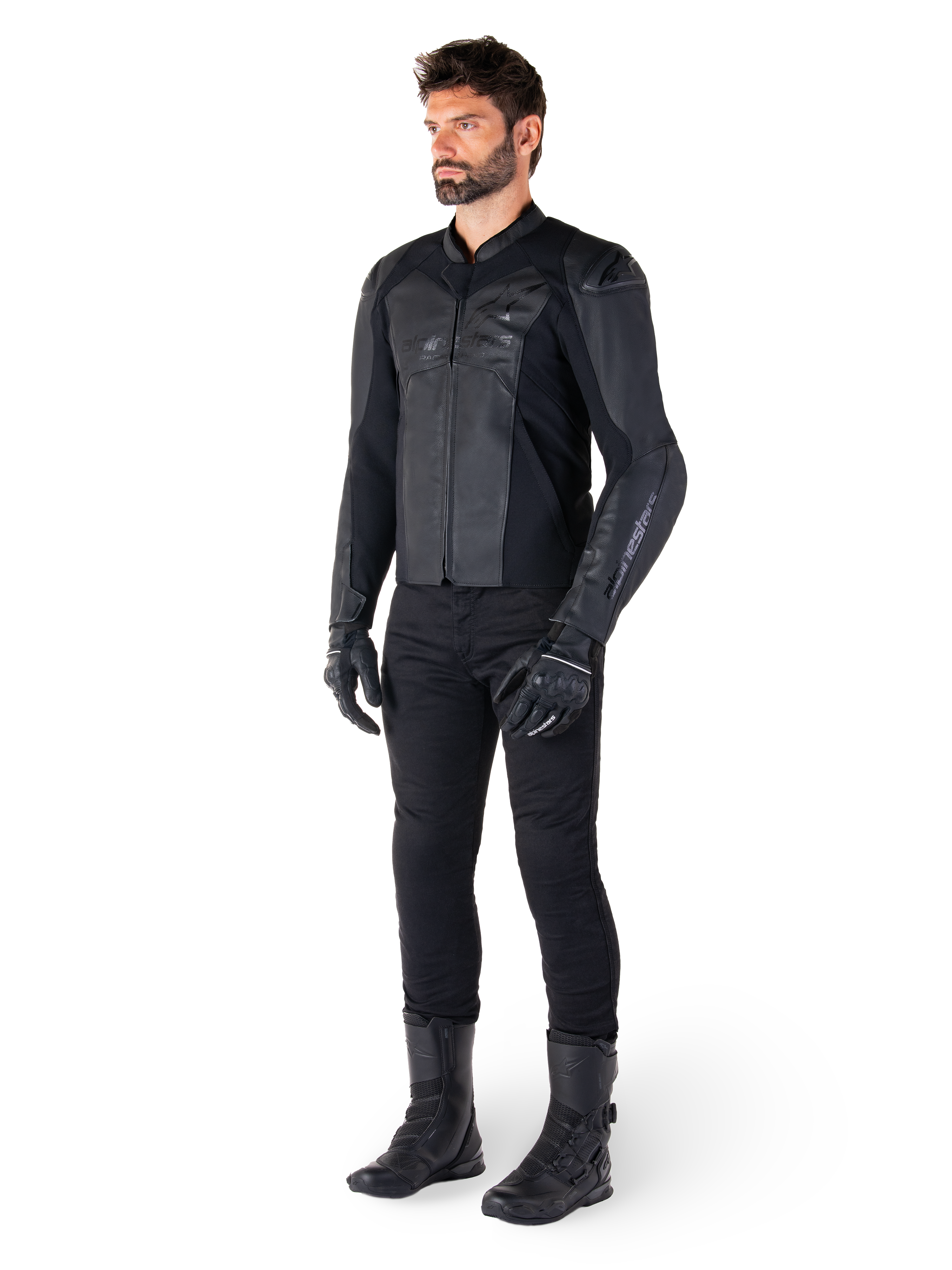 Alpinestars Faster V3 läderjacka, helsvart, bärs med svarta byxor, handskar och stövlar, med en teknisk läderkonstruktion, HRSF-stretchpaneler, integrerade DFS GP Lite-axelskydd och en stilren sportig silhuett.