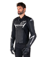 Alpinestars Faster V3 Leather Jacket, Sport Riding Motorcycle Jacket, Black and White, prominent white Alpinestars logo and 'Racing Ahead' text on the chest, star logos on the shoulders, premium leather construction with stretch panels, worn by a model with black pants and gloves