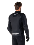 Alpinestars Faster V3 Leather Jacket, Black and White, rear view on a rider, featuring white star logo on the upper back and large Alpinestars branding with "Racing Ahead" on the lower tail, elongated rear for riding coverage, premium sport leather construction