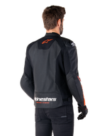 Alpinestars Faster V3 Airflow läderjacka, sportig motorcykeljacka, svart med röd fluo, vy bakifrån, med perforerade läderpaneler, orangeröd Alpinestars-logotyp på övre ryggen och vit logotyp på nedre ryggen, bärs med svarta byxor och handskar, strömlinjeformad racinginspirerad stil