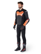 Alpinestars Faster V3 Airflow läderjacka, svart och röd fluo, bärs av en manlig modell med svarta motorcykelbyxor, handskar och racingstövlar, med perforerat läder och en sportig siluett.