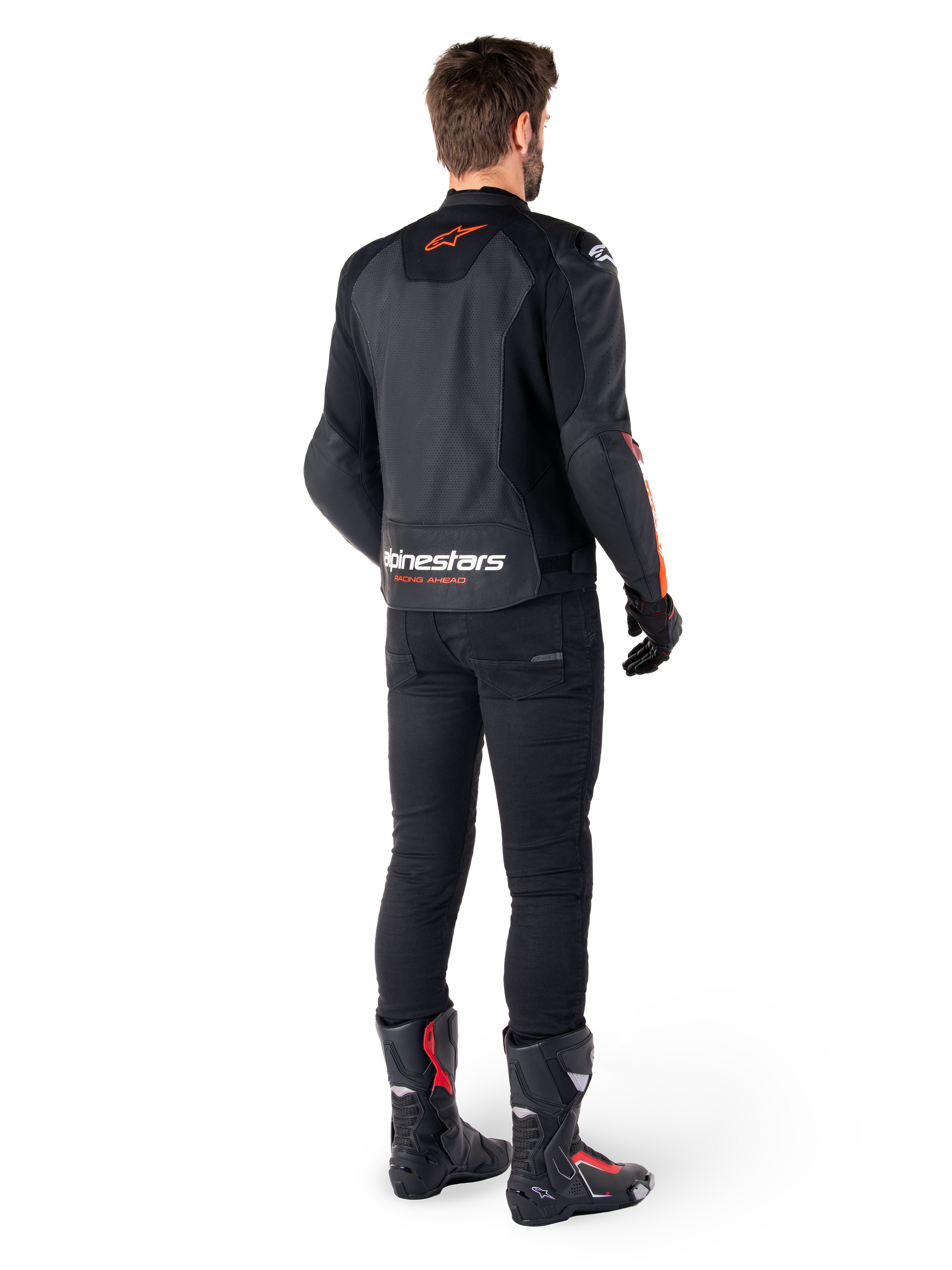 Alpinestars Faster V3 Airflow läderjacka, svart och röd fluo, sedd bakifrån på en förare, med perforerade läderpaneler och framträdande logotyper, bärs med svarta byxor och motorcykelstövlar, sportig mc-utrustning