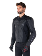 Modell som bär Alpinestars Faster V3 Airflow Läderjacka i Black Black, sportig MC-jacka i läder med perforerat läder och stretchpaneler, matchad med svarta byxor och svarta handskar med röda detaljer, stilren racing-inspirerad design