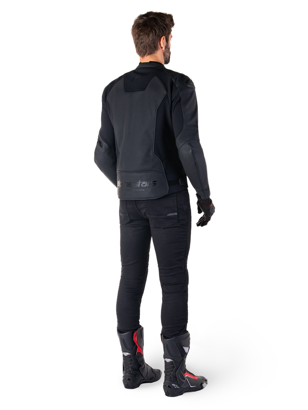 Alpinestars Faster V3 Airflow läderjacka, svart, baksida av en man som bär en sportig läderjacka med perforerade ryggpaneler och Alpinestars-logotyp, stylad med svarta körbyxor och svarta och röda stövlar.