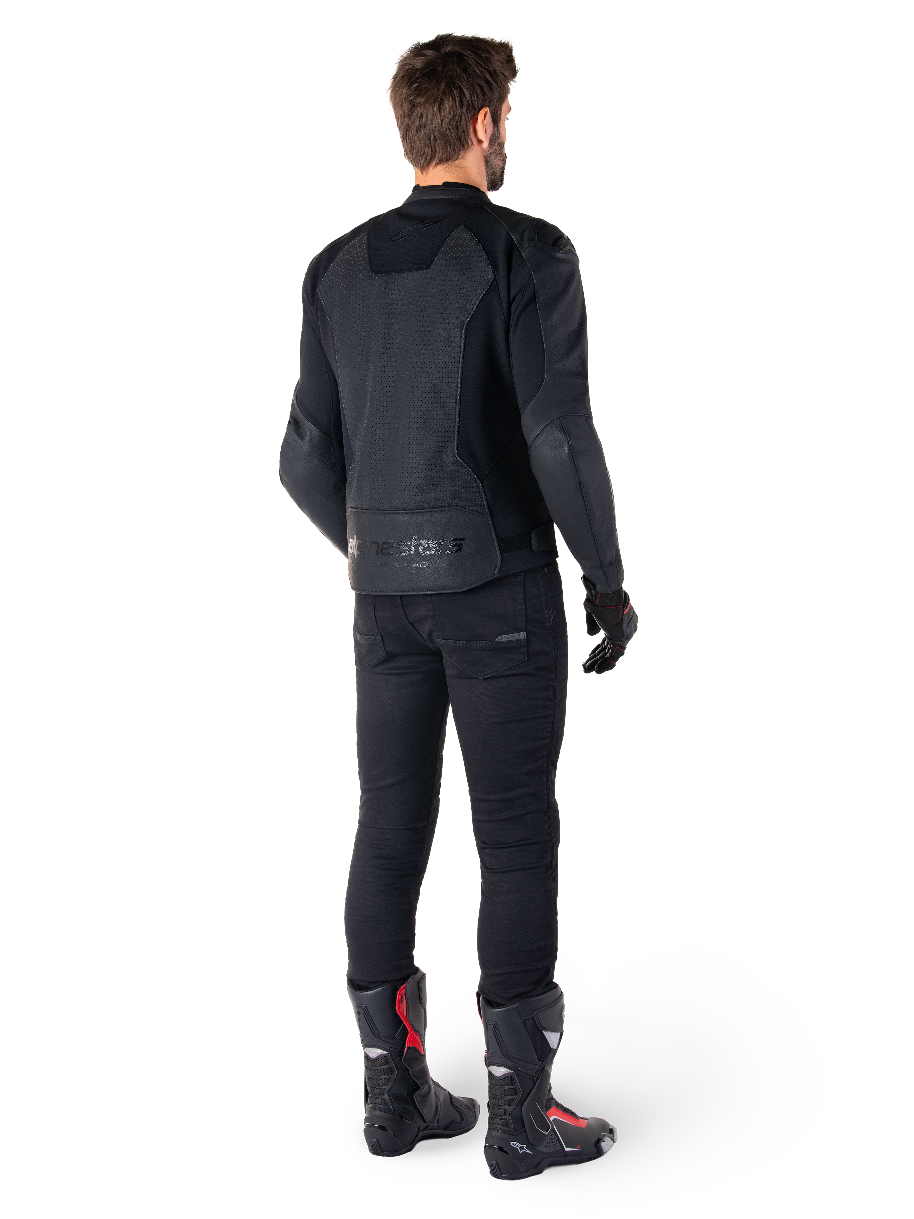 Alpinestars Faster V3 Airflow läderjacka, svart, baksida av en man som bär en sportig läderjacka med perforerade ryggpaneler och Alpinestars-logotyp, stylad med svarta körbyxor och svarta och röda stövlar.