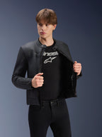 Alpinestars Dyno läderjacka, svart, bärs av en manlig modell över en svart t-shirt med logotyp, motorcykeljacka i förstklassigt nötläder med arvsinspirerad design, subtila ränder över bröstet och modern urban passform