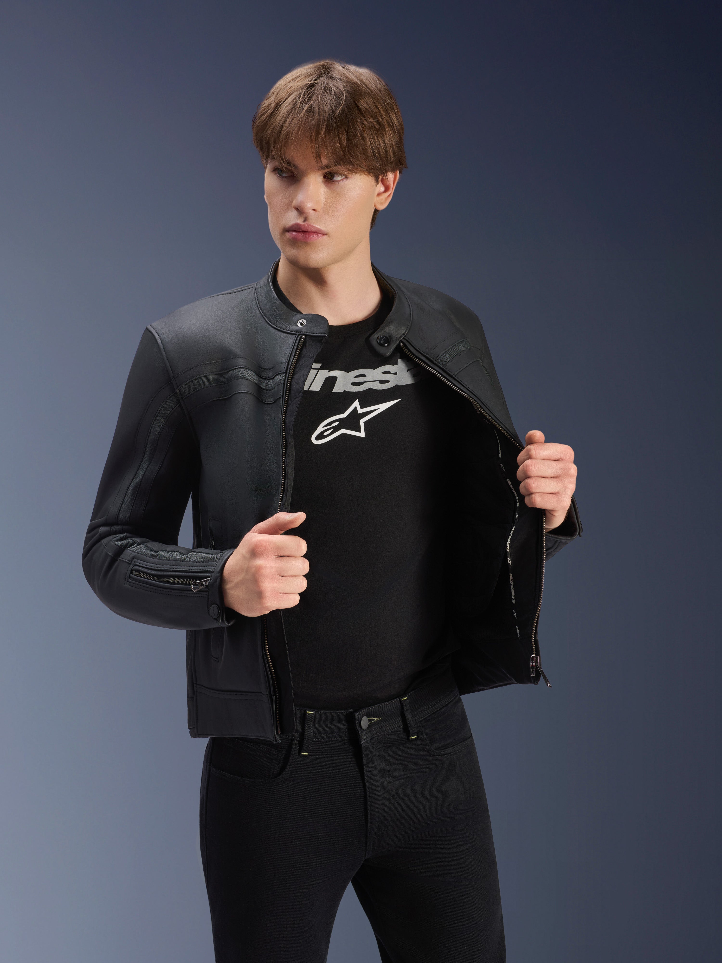 Alpinestars Dyno läderjacka, svart, bärs av en manlig modell över en svart t-shirt med logotyp, motorcykeljacka i förstklassigt nötläder med arvsinspirerad design, subtila ränder över bröstet och modern urban passform