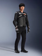 Alpinestars Atem V5 läderjacka, motorcykeljacka för racing, svart och vit, bärs med svarta byxor och matchande handskar, med vit Alpinestars-logotyp över bröstet och skyddande axelskydd.