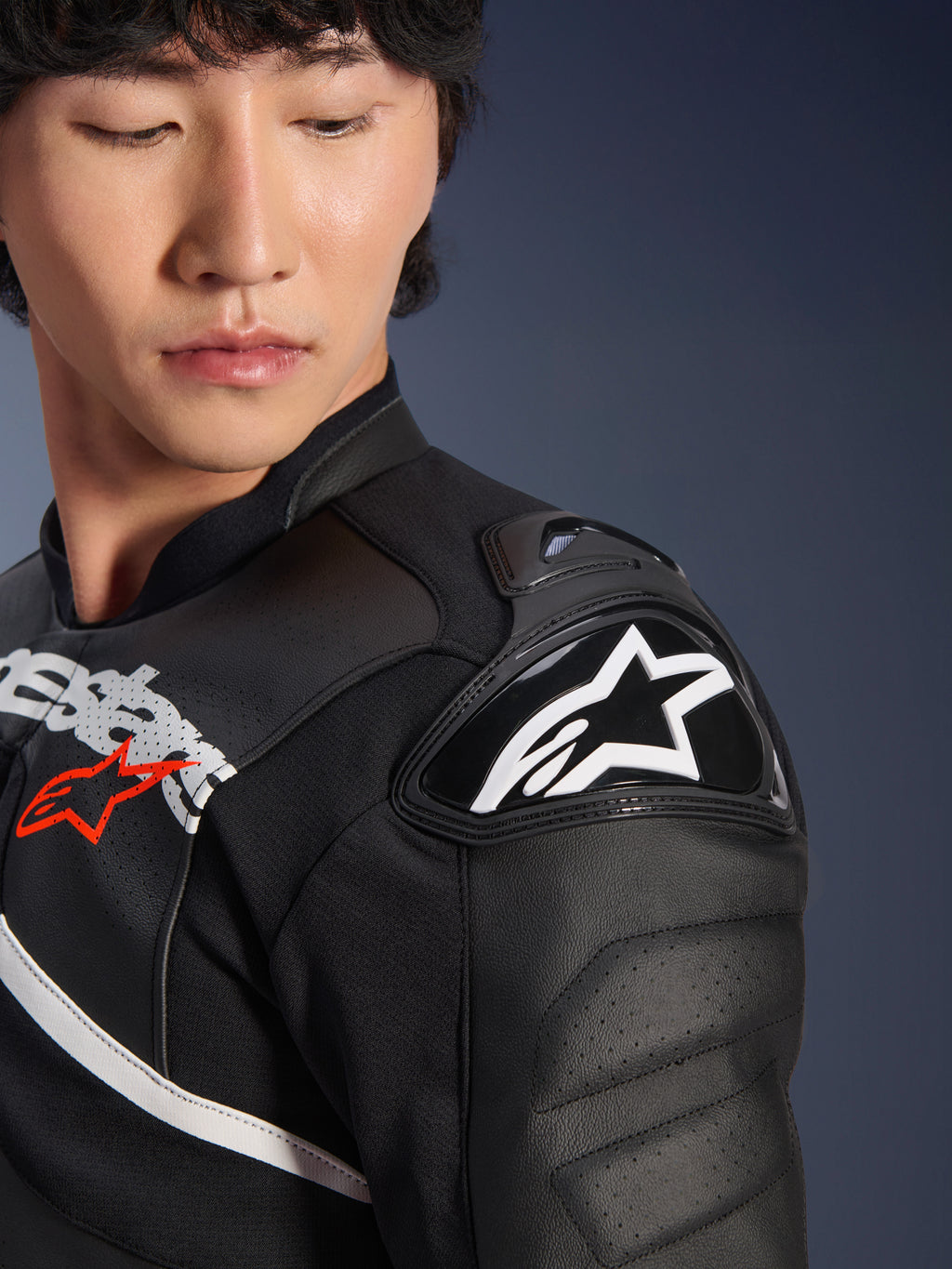 Närbild på Alpinestars Atem V5 läderjacka i svart och vitt, med DFS RR-axelskydd med vit stjärnlogotyp, perforerad läderkonstruktion och racinginspirerad bröstgrafik