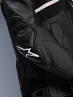 Alpinestars Atem V5 Läderjacka, svart och vit, närbild på DFS RR-armbågsskyddet med vit stjärnlogotyp, med dragspelsläder och perforerade texturer för sportkörning