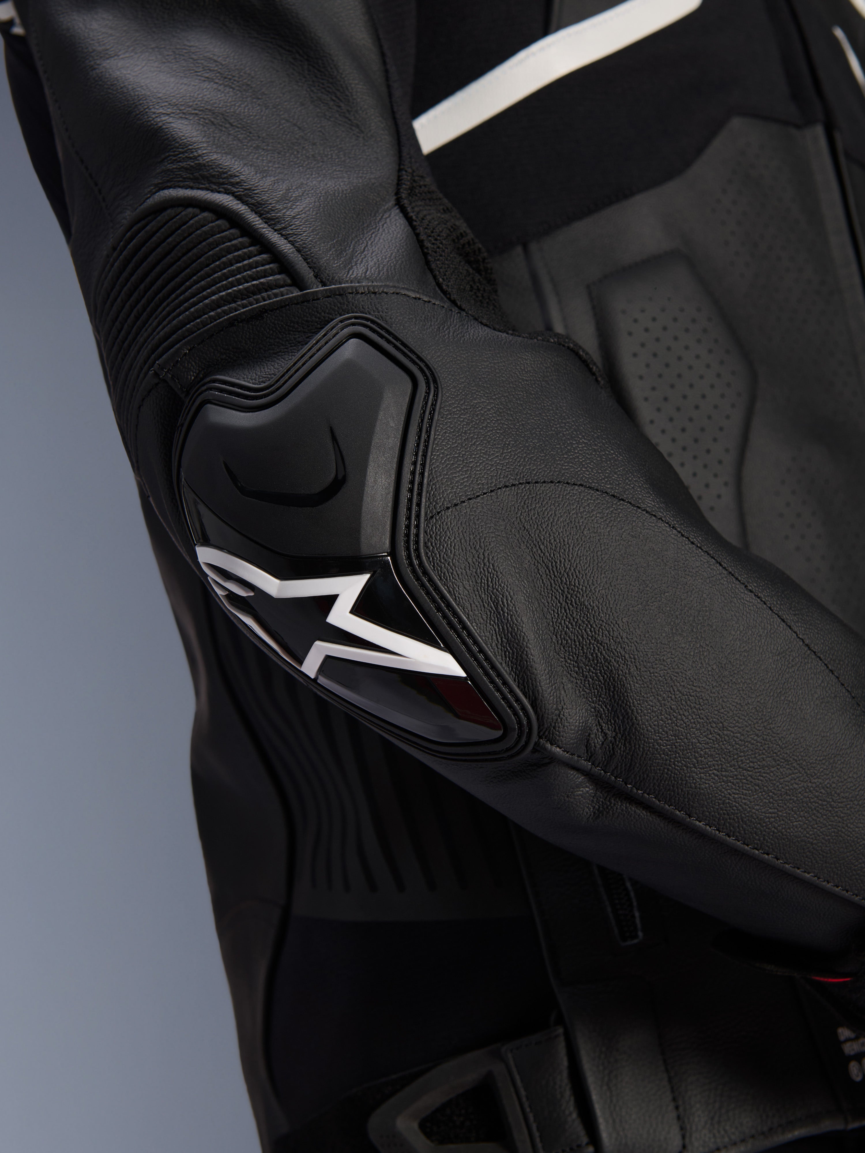 Alpinestars Atem V5 Läderjacka, svart och vit, närbild på DFS RR-armbågsskyddet med vit stjärnlogotyp, med dragspelsläder och perforerade texturer för sportkörning
