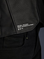 Närbild av Alpinestars Atem V5 läderjacka i svart, med den nedre ryggpanelen, 'ONE GOAL. ONE VISION. VENICE / LOS ANGELES CALIFORNIA'-tryck och perforerad läderstruktur.