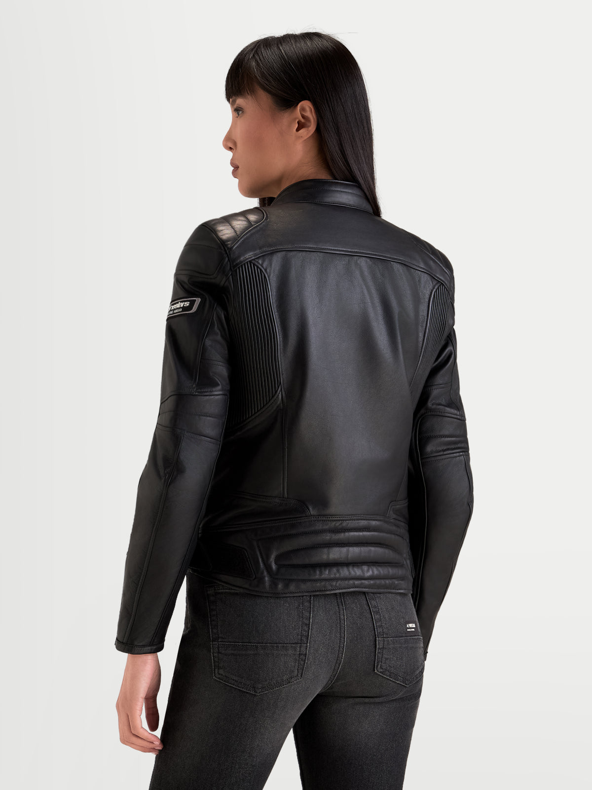 Alpinestars Revea dam läderjacka, svart motorcykeljacka i urban stil, vy bakifrån som visar premiumläder och axelvaddering buren av en modell