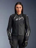 Kvinnlig modell i Alpinestars Stella Dusk läderjacka, motorcykeljacka för dam i svart och vitt, med premium läderkonstruktion, vadderat bröst- och axelskydd och dragkedja fram, stylad med svarta körhandskar.