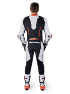 Alpinestars GP-R7 skinnställ, racingoverall i vitt och svart nötläder, vy bakifrån med aerodynamisk puckel och röd fluo-grafik.