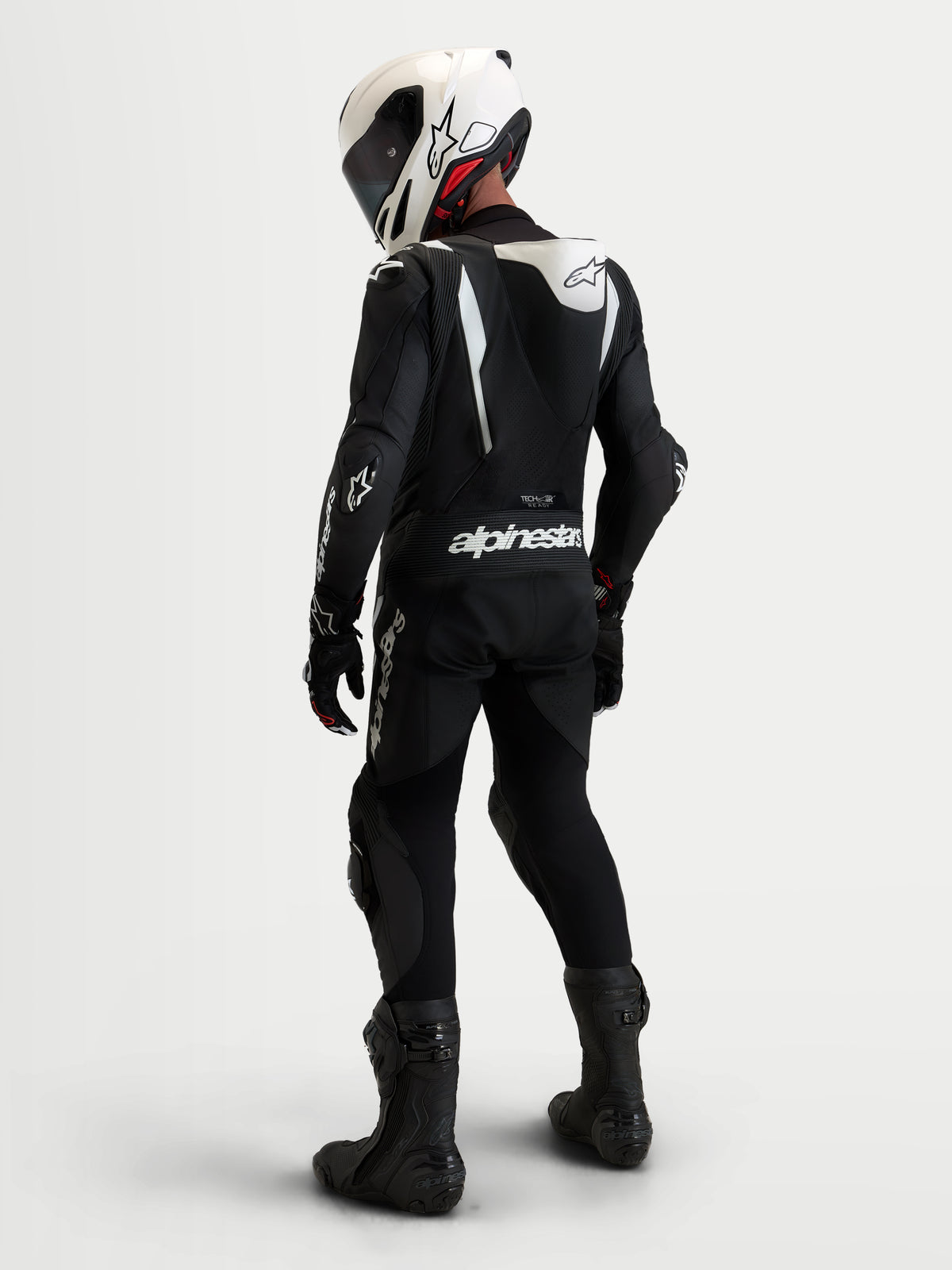 Alpinestars Missile V3 skinnställ 1-delat, svart och vitt motorcykelracingställ med aerodynamisk puckel och matchande hjälm, vy bakifrån