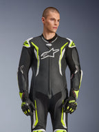 Alpinestars GP Tech V5 endels skinnställ, svart, vit och neongul, professionell racingutrustning, perforerat läder med stor vit Astar-logotyp på bröstet, neongula och vita detaljer, bärs med matchande racinghandskar