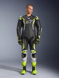 Alpinestars GP Tech V5 skinnställ, professionell motorcykelracingoverall i svart och neongul fluo med vita detaljer, bärs av en modell med matchande racinghandskar och stövlar, med aerodynamisk design och skyddande sliders.