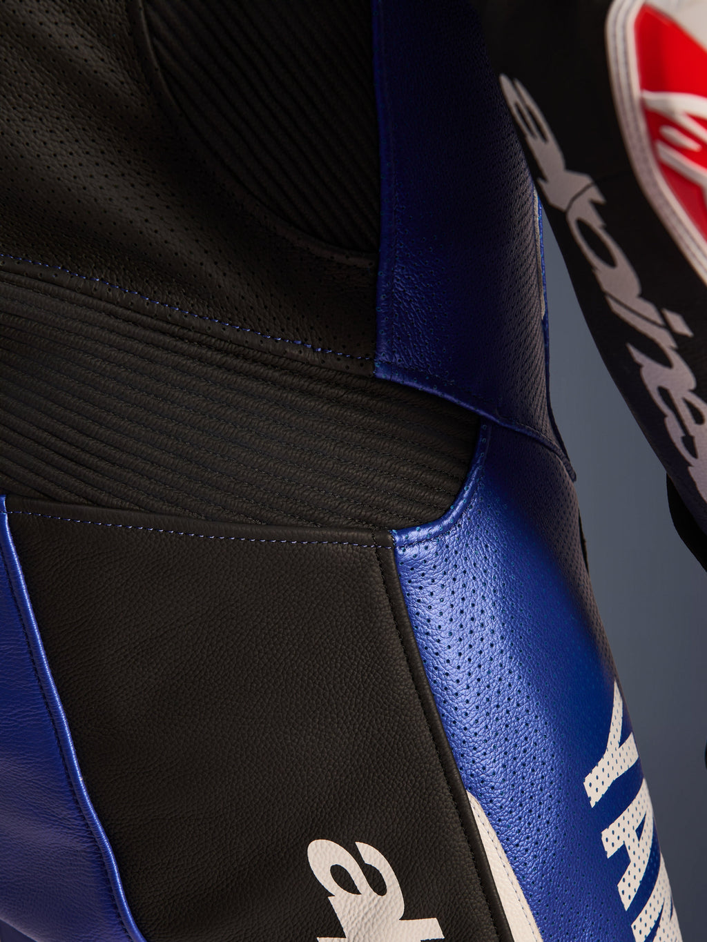 Närbild på Alpinestars Yamaha GP-R7 helställ i läder, metallicblå och svart, med perforerade läderpaneler för ventilation, svarta dragspelspaneler för flexibilitet och tydlig vit Yamaha-logotyp, konstruktion i högkvalitativt nötläder.