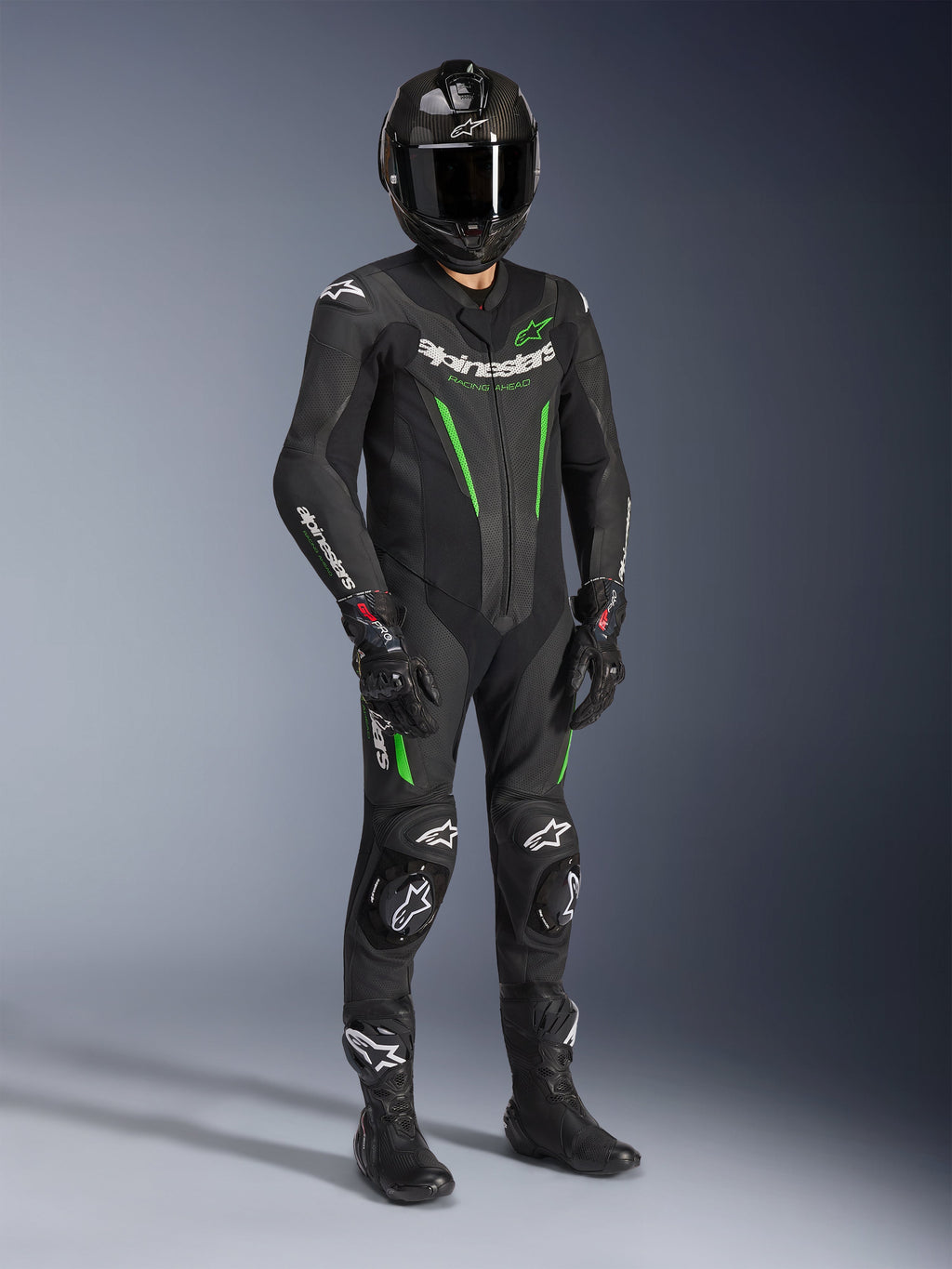 Alpinestars GP Force V2 Leather Suit - 1Piece, svart och grön, bärs med matchande svart hjälm, racinghandskar och stövlar, med klargröna detaljer och tydlig vit Alpinestars-logotyp, professionell utrustning för bana och sportig körning