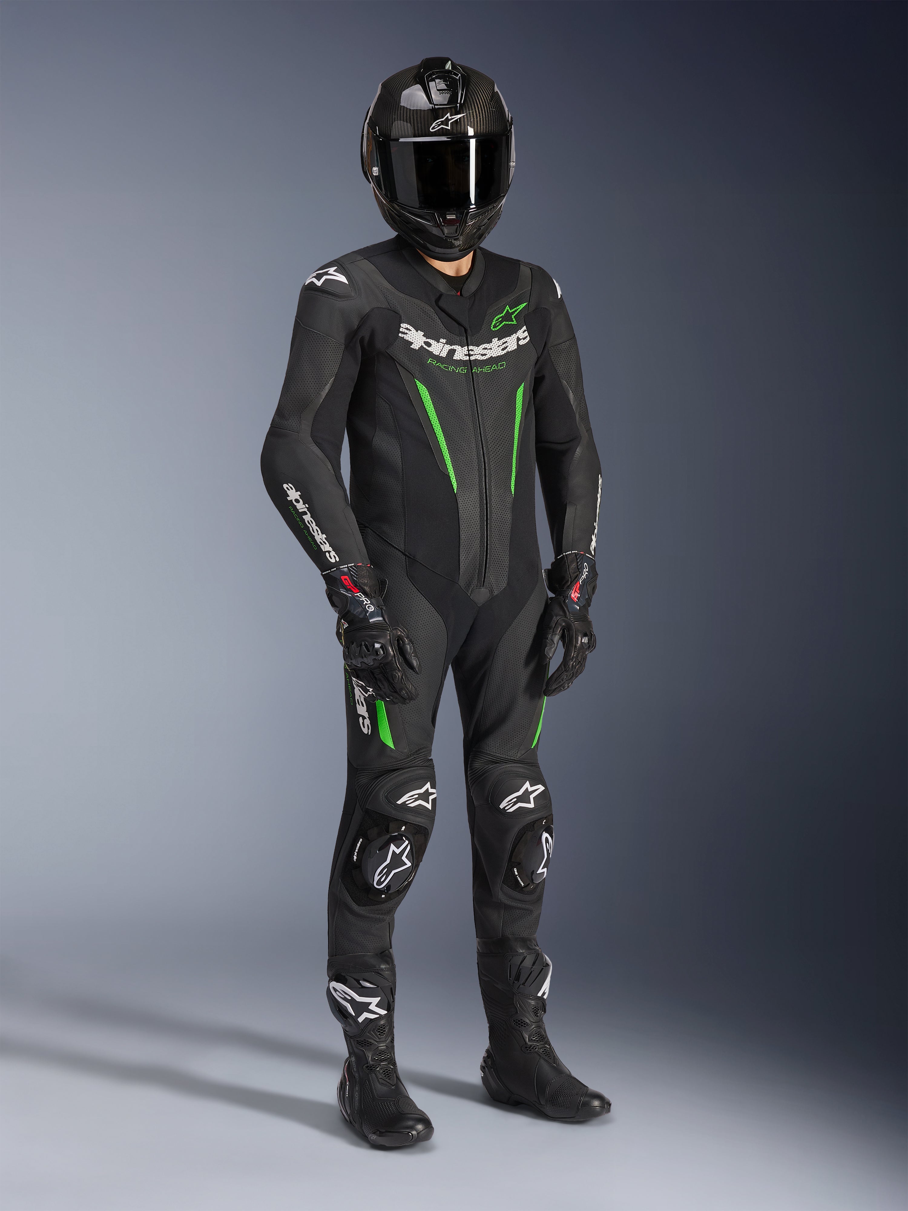 Alpinestars GP Force V2 Leather Suit - 1Piece, svart och grön, bärs med matchande svart hjälm, racinghandskar och stövlar, med klargröna detaljer och tydlig vit Alpinestars-logotyp, professionell utrustning för bana och sportig körning