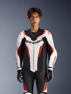 Alpinestars GP Force V2 läderställ - 1 del, vit, svart och röd fluo, bärs av en manlig modell, med perforerade läderpaneler och tydlig Alpinestars-logotyp på bröstet, kombinerat med svarta och vita racinghandskar, designat för bana- och prestandakörning