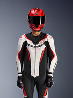 Alpinestars GP Force V2 skinnställ - 1 del, vit, svart och röd fluo, bärs med röd integralhjälm och svarta racinghandskar, perforerade läderpaneler och framträdande Alpinestars-logotyp på bröstet, professionell racingutrustning för motorcykel