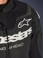 Alpinestars GP Force V2 2-Piece Leather Suit, Racing/Sport Motorcycle Suit, Black, close-up of perforated leather chest with white Alpinestars logo and branding, highlighting ventilation holes and textured construction.