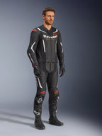 Alpinestars GP Force V2 2-Piece Leather Suit, Black White and Red Fluo, worn by a model with black racing boots and gloves, featuring perforated leather panels, white aerodynamic accents, and red fluo logos on shoulders and knees, professional motorcycle racing gear