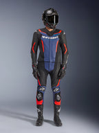 Alpinestars GP Force V2 läderställ, 2-delat, svart, blå och röd fluo, bärs med en helhjälm i kolfiber, svarta racinghandskar och stövlar, med blå bröstpaneler och rödfluorescerande detaljer, professionell racingutrustning för motorcykel