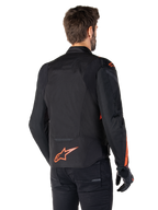 Manlig modell bär Alpinestars T-Jaws V4 Waterproof Jacket sedd bakifrån, svart med fluoröda detaljer, med en fluoröd logotyp på nedre delen av ryggen och detaljer på axlar och ärmar, sportig motorcykelutrustning.