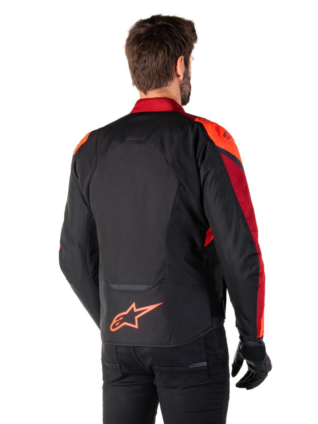 Rear view of a man wearing the Alpinestars T-Jaws V4 Waterproof Jacket in Black Red Fluo Dark Red, featuring vibrant red accents on the shoulders and sleeves, a fluo red Alpinestars logo on the lower back, paired with black pants and gloves.