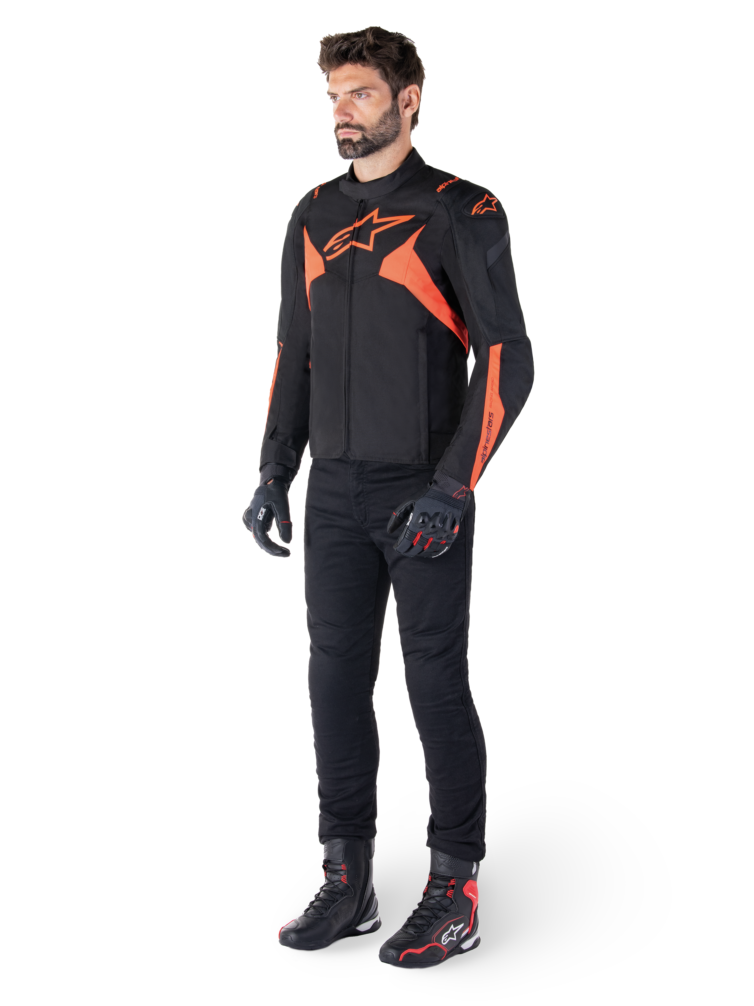 Alpinestars T-Jaws V4 Waterproof Jacket, svart och röd fluo, bärs av en manlig modell med svarta byxor, handskar och stövlar, med lysande orangea detaljer och Alpinestars-logotyp, sportig design för motorcykelkörning