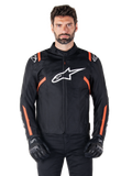 Alpinestars T-SPS V2 Waterproof-jacka, svart, vit och röd fluo, bärs av en manlig modell med svarta mc-handskar, med en stor vit Alpinestars-logotyp på bröstet och livfulla orangea detaljer på axlar och ärmar.