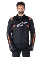 Alpinestars T-SPS V2 Waterproof-jacka, svart, vit och röd fluo, bärs av en manlig modell med svarta mc-handskar, med en stor vit Alpinestars-logotyp på bröstet och livfulla orangea detaljer på axlar och ärmar.